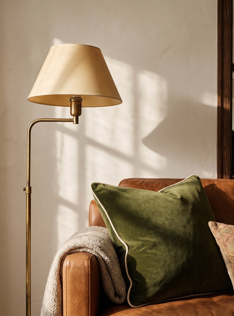 Olive green piped velvet cushion on an armchair beside a floor lamp