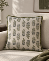 Moss piped cushion with a green leaf block print on a cream armchair