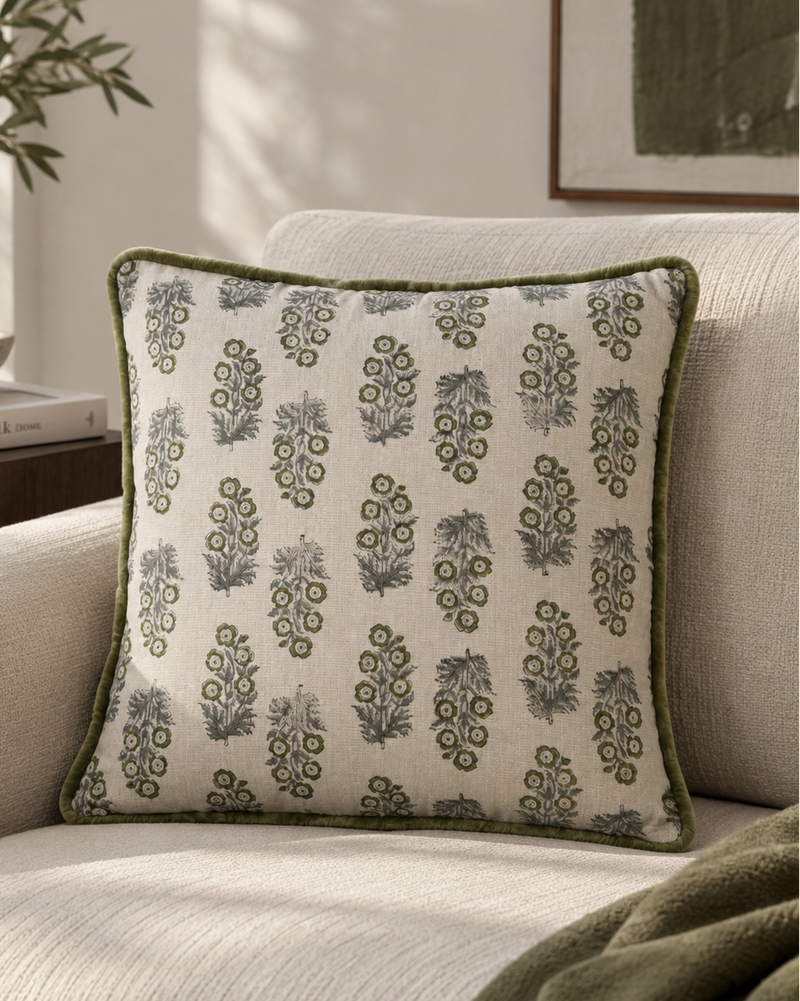 Moss piped cushion with a green leaf block print on a cream armchair