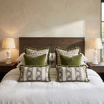 Green frill lumbar cushions with matching square cushions on a bed between bedside lamps
