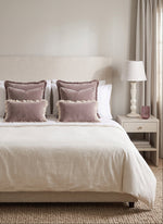 Warm white Bloom mango wood lamp in a bedroom with mauve cushions