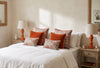 Burnt orange Ember mango wood lamp on a bedside table beside a made bed