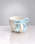 White textured ceramic mug with a powder blue ribbon bow handle