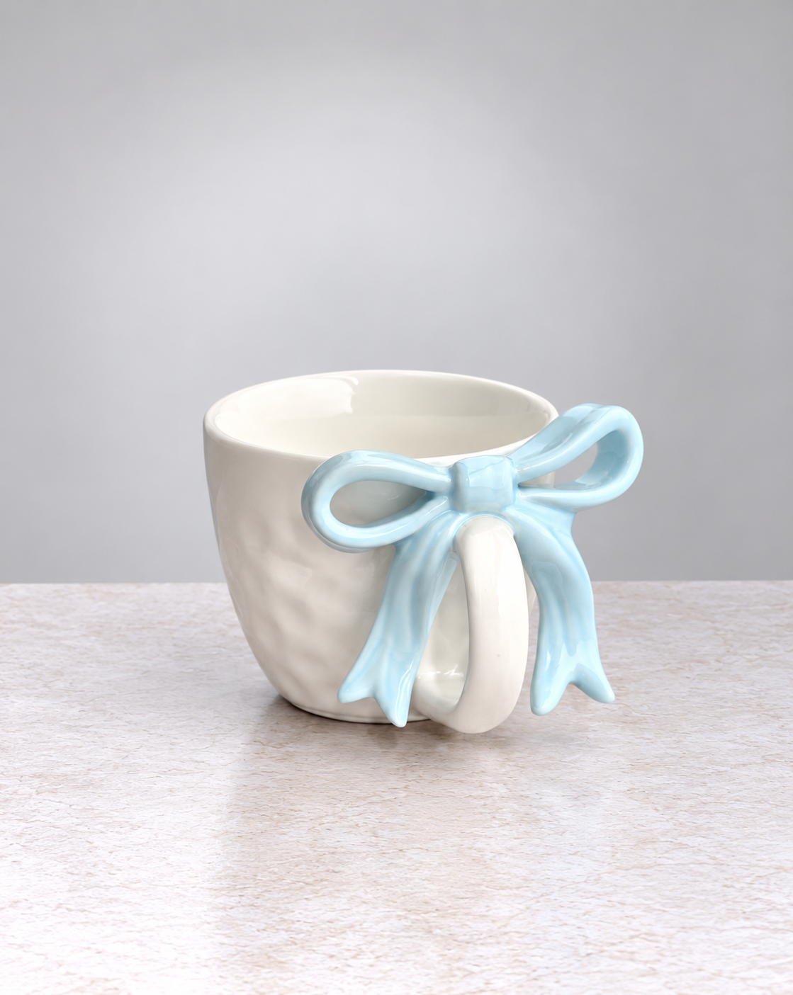 White textured ceramic mug with a powder blue ribbon bow handle