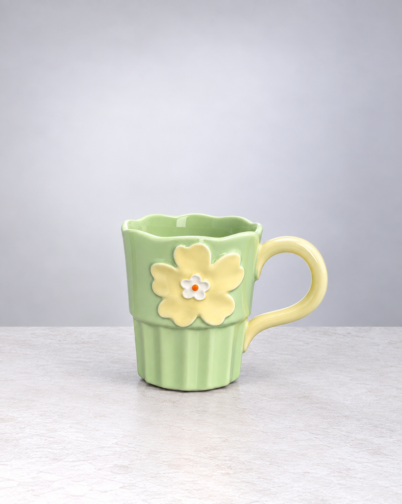Sage green Blossom ceramic mug with a raised yellow flower and fluted base, on white