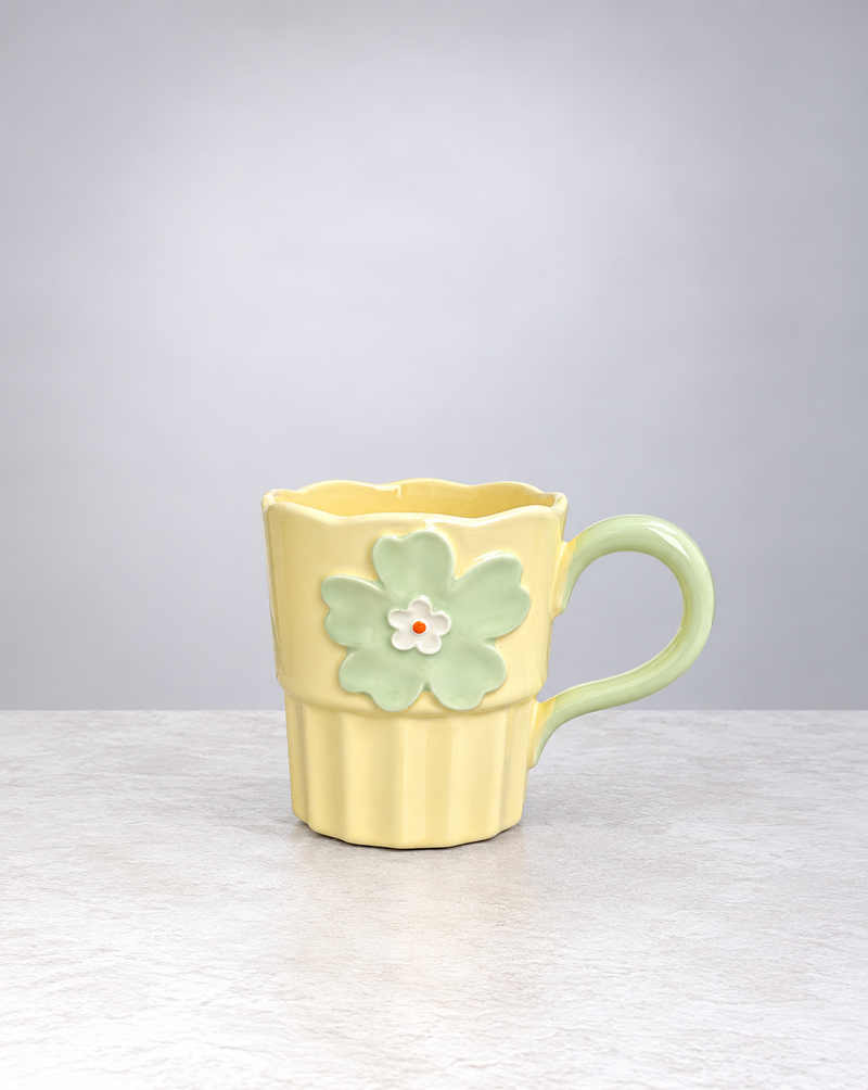Butter yellow Blossom ceramic mug with a raised green flower and fluted base, on white